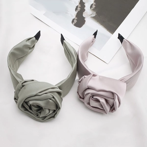 Elegant satin flower headbands in sage green and dusty pink on a white fabric base
