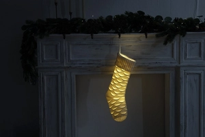 Detail of cream white knit Christmas stocking with hollow pattern hanging by a fireplace