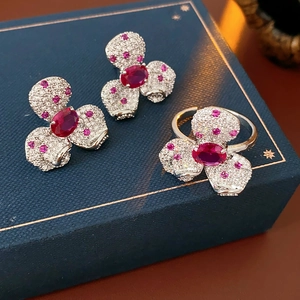 Detail of silver clover jewelry set with red gemstones and crystals in a premium blue box