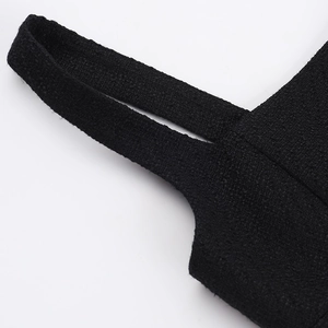 Close-up detail of high-quality black tweed fabric and shoulder strap on stylish dress
