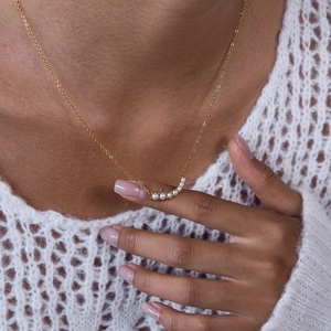 Detail of 18K gold stainless steel necklace with elegant pearl smile pendant on model