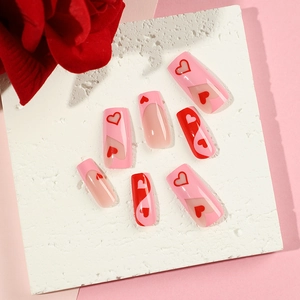 Pink heart press-on nails with French tips and red rose on a textured white display