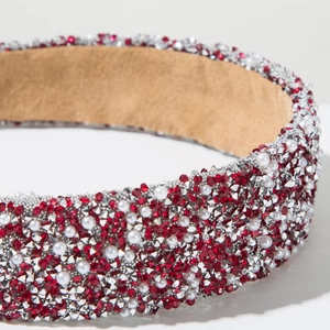 Macro shot of handmade headband with red crystals and pearls on tan velvet lining