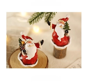 Nahaufnahme von zwei Miniatur-Weihnachtsmannfiguren auf einem gemütlichen Holzsockel