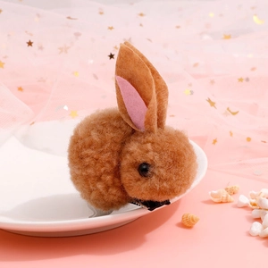 Close-up of a brown plush bunny hair clip with pink ears on a decorative pink background
