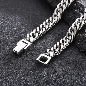 Macro shot of silver Cuban link chain with square clasp on black rock texture