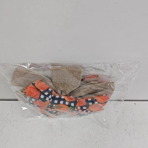Detail of burlap Thanksgiving bow with orange pumpkin pattern and black white plaid accent