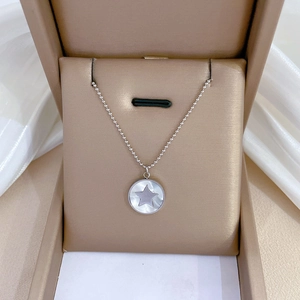 Gros plan d'un collier en acier titane avec pendentif étoile en nacre dans un écrin