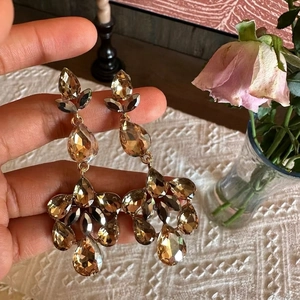 Detailed close-up of champagne crystal drop earrings with long tassels and gold finish