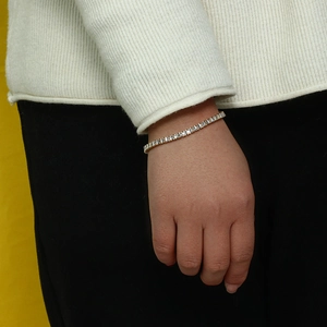 Détail d'un bracelet de tennis doré avec zircons blancs porté au poignet d'une femme