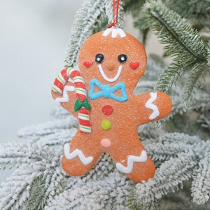 Glittery gingerbread man Christmas tree ornament with candy cane on snowy branch
