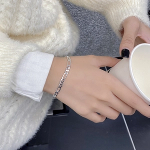 Close-up of 925 sterling silver Figaro bracelet on wrist with a cozy white sweater