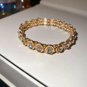 Macro detail of sparkling crystal oval stretch bracelet with gold plated metal finish