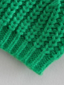 Primo piano del maglione in maglia verde erba che mostra la trama del filato spesso