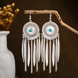 Ethnic silver-finish tassel earrings with turquoise stone hanging on a branch
