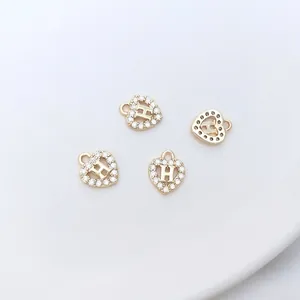 Close-up of 14K gold plated heart charms with micro-pave zircons and H-letter detail