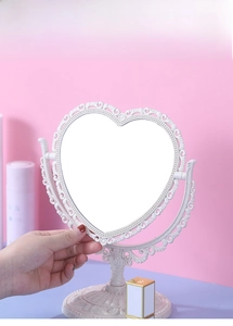 Macro detail of white heart-shaped vanity mirror with ornate vintage floral carvings