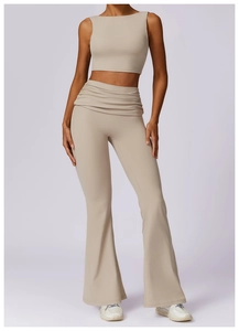 Detail of high-waisted beige yoga pants with textured waistband and flared leg design