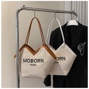 Detail view of woven straw tote bags with contrast leather trim and MOBORN PARIS logo