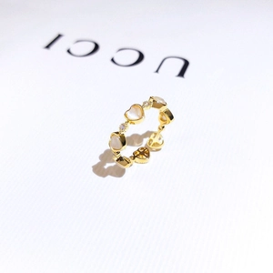 Macro detail of gold plated heart ring featuring mother of pearl and cubic zirconia stones