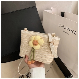Detail of woven straw bucket bag featuring a yellow sunflower and adjustable strap