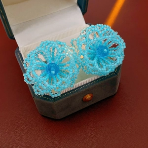 Detail of blue beaded flower earrings displayed in a dark green velvet jewelry gift box