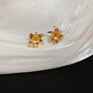 Elegant gold lily flower stud earrings with matte and polished texture on silk fabric