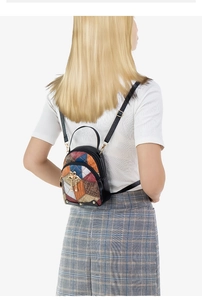 Detail view of a color-block small backpack with faux leather texture and metallic zippers