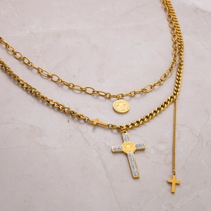 Close-up of gold double-layer necklace with rhinestone cross and Saint Benedict medal