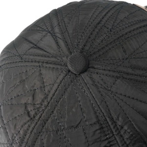 Detail of black quilted winter cap showing thermal fabric texture and fine diamond stitching