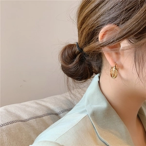 Detail of gold layered geometric hoop earring worn by a model in soft lighting