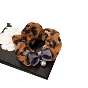 Leopard print knit scrunchie with purple velvet bow and pearl pendant on a box
