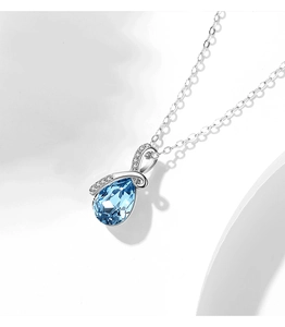 Macro shot of silver ribbon necklace with a pear-cut blue zircon pendant and sparkling stones