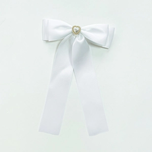 Détail de la barrette à nœud en satin blanc avec perle en cœur et longs rubans
