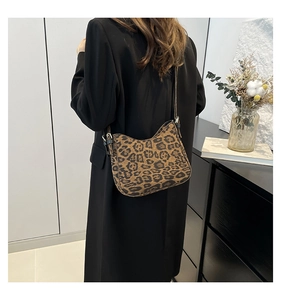Close-up of leopard print crossbody bag in brown suede finish on a black coat