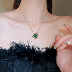 Close-up of gold necklace with square green gemstone pendant on model neck