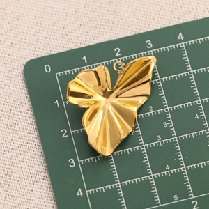 Detail shot of a golden stainless steel sunflower pendant on a measuring mat