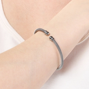 Macro detail of silver mesh woven stainless steel open cuff bracelet with bead ends