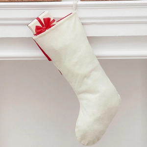 Close-up of a cream velvet Christmas stocking with a gift box on a white mantel