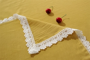 Close-up of yellow washed cotton tablecloth with delicate white lace border detail