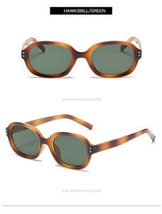 Close-up of hawksbill oval sunglasses with green lenses and decorative silver studs
