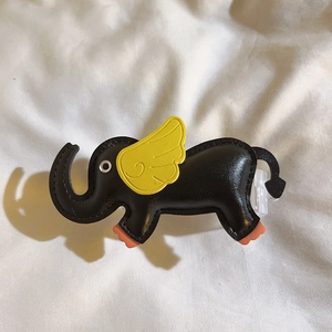 Detail of a handmade black leather elephant charm with yellow wings and orange feet accents