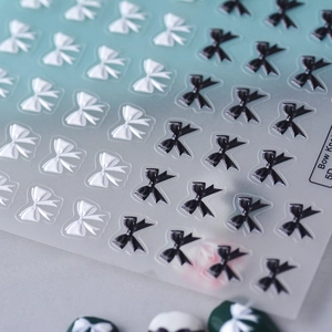 Macro shot of 5D embossed black and white bow knot nail stickers with 3D texture