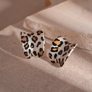 Detailed view of C-shaped earrings with leopard print on a textured stone background