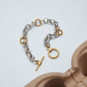 Close-up of two-tone 18K gold and silver stainless steel chain bracelet with toggle clasp