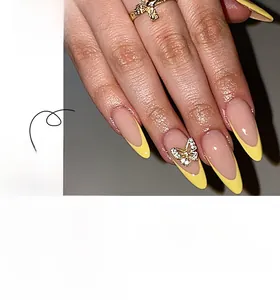 Detail of yellow French long almond press-on nails featuring 3D gold butterfly rhinestones