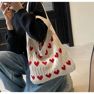 Selfie frente al espejo mostrando el tamaño del bolso de punto con corazones al hombro