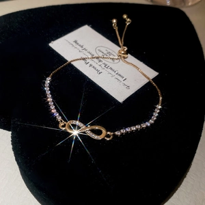 Macro detail of a gold infinity bracelet with micro-pave zircons on a velvet stand