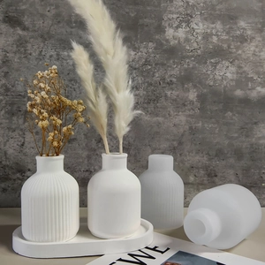 Detail of white minimalist ceramic mini vase set with ribbed texture on a concrete tray