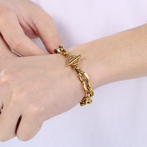 Detail of a gold Cuban chain bracelet with OT toggle clasp worn on a woman's wrist